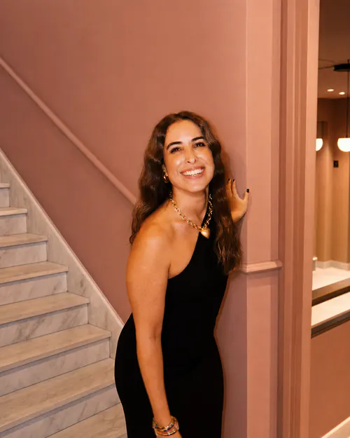 Isa de pie junto a una escalera de mármol, con vestido negro